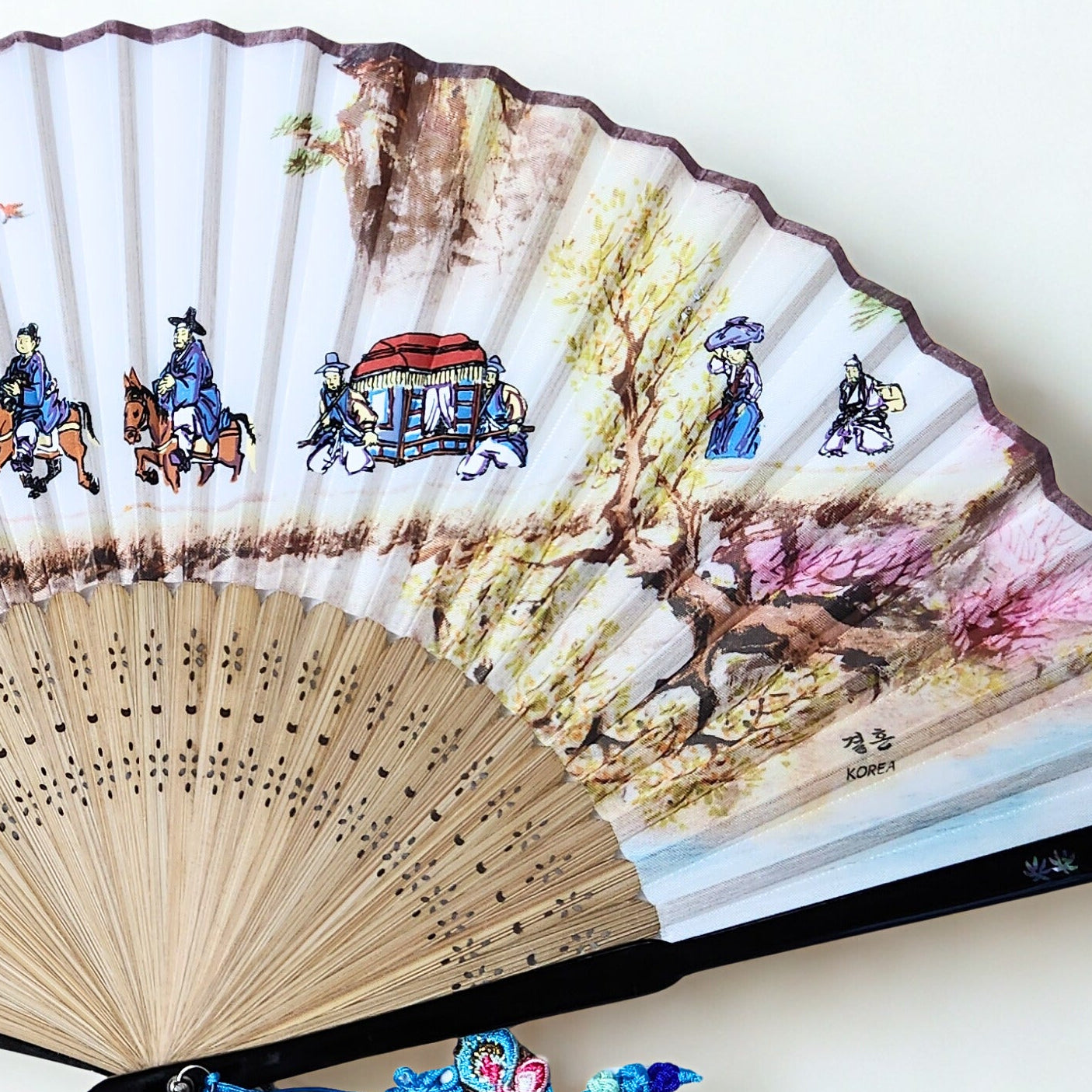 Traditional Korean folding fan with artistic design on a white background